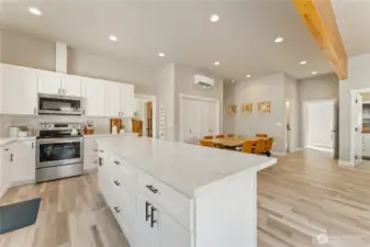 View 3 of kitchen w/ high-end appliances, quartz countertops & sit up bar looking towards the spacious dining room that comfortably seats 8 guests.