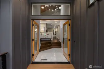 The entrance features French doors and an elegant oversized chandelier—setting the tone for modern sophistication throughout.