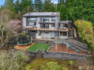 Spacious backyard boasts a grassy play area, large playset, full-size trampoline, and terraced garden spaces that benefit from the abundant western light!