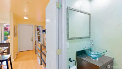 The remodeled half bath near the entry features a stunning vessel sink and a sleek, tapered vanity with storage - proof that even the small spaces shine.