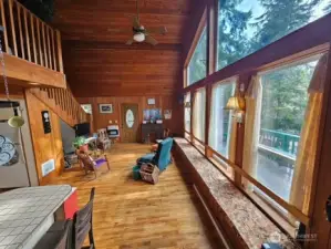 Vaulted ceiling living room flooded with light from the wall of windows.