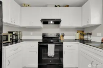 Modern kitchen with black appliances and counter tops.