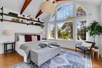 Primary bedroom with dramatic windows, vaulted ceiling, and a luxurious attached bathroom