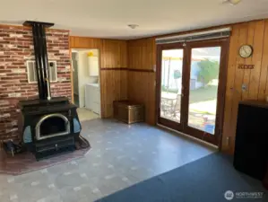 Large Wood burning stove to keep house cozy is found in living room vynal flooring in high traffic area. French doors lead to fully fenced backyard.