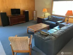 Lots of room for couches and entertainment center and exercise equipment. Wood panel walls. Attic stairway here leads to lots of storage above.