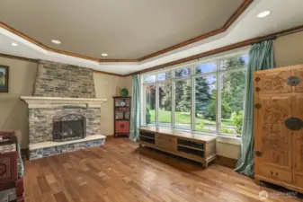 Formal living room with double crown molding, stone surround masonry fireplace with raised hearth and hardwood floors.