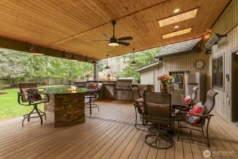 Outdoor Entertaining designed for year-round enjoyment, full outdoor kitchen with slab granite counters, a gas BBQ, Teppanyaki griddle, 32K BTU stovetop burner, refrigerator, storage bins, and a built-in fire pit island.