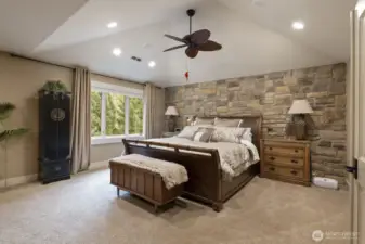 The tranquil primary suite with a stone bed wall.