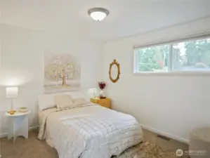 Cozy bedroom with large window, soft bedding, and elegant decor.