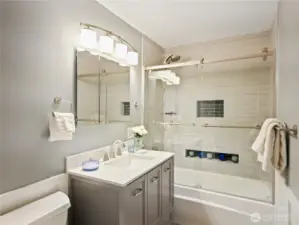 Modern bathroom with glass-enclosed tub/shower and vanity sink.