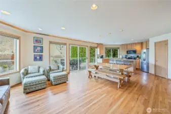 Open-concept main level featuring hardwood floors, multiple seating areas, and sliding doors leading to the waterfront deck.