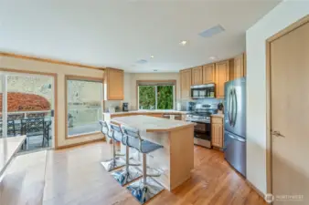 Open kitchen with center island seating, stainless steel appliances, and direct access to the upper deck for effortless indoor-outdoor living.