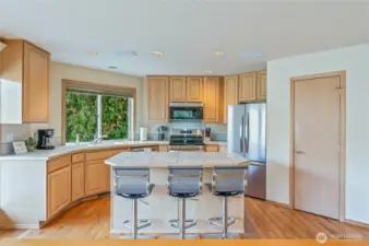 Expansive kitchen layout with island seating, generous counter space, and large windows providing natural light and river views.