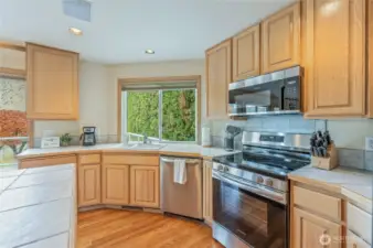 Kitchen with stainless steel range, ample cabinetry, and backyard greenery views from the sink.