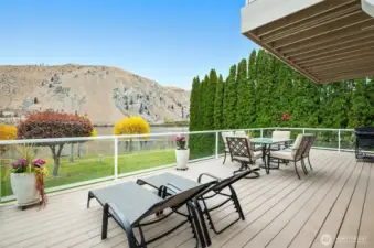 Expansive composite deck with lounge chairs and outdoor dining space overlooking the Columbia River. A serene setting for morning coffee, evening barbecues, and all-season enjoyment.