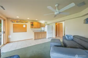 Lower-level wet bar with full-size refrigerator, cabinetry, and tile flooring — ideal for hosting guests or creating a self-contained guest level. Opens to the rec room and patio.