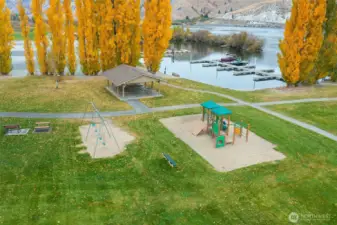 Sun Cove’s riverside park featuring a covered picnic pavilion, swings, play structure, benches, and easy access to the marina — the perfect spot for gatherings, playtime, or sunset walks.