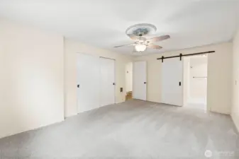 Another view of the primary bedroom showing the stylish barn door leading to the private bath.
