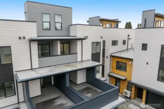 A rear view of the home reveals the spacious dual patio design and clean, modern architecture.