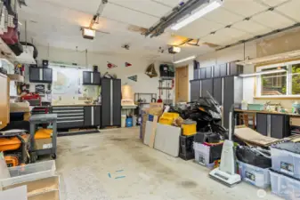 Double garage with a utility sink, lots of shelving, workshop space, great lighting and cabinetry