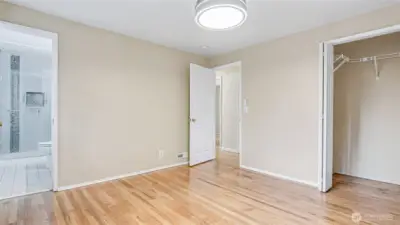 Another view of the primary with glimpses of the closet and en-suite bathroom.