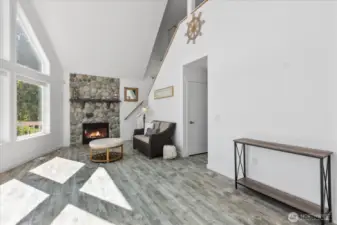 Living room with cathedral ceiling & cobblestone propane fireplace to stay cozy on cold evenings.