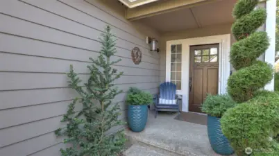 Welcoming front entry with charming greenery, stylish planters, tranquil water feature, and a cozy seating nook that sets the tone for the home.