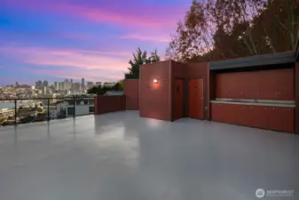 Large rooftop deck has built in cabinets, a kitchen sink, and storage shed