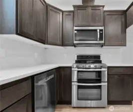 Sleek stainless steel Whirlpool appliances include a microwave, gas double oven and dishwasher.