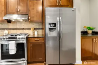 Stainless steel appliances highlight the kitchen; including a four burner gas cooktop with a griddle in the middle, and a  café door refrigerator with water & ice on the door.