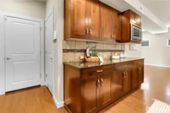 Across the walkway from the pantry, and next to the refrigerator, is a food staging area that has an additional countertop with cabinets below.  It's a dedicated spot for plating or arranging dishes before they are presented to the table.