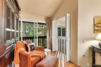 Seating area in primary bedroom has louvered doors to look below into living room and a Juliet balcony to enjoy the view.