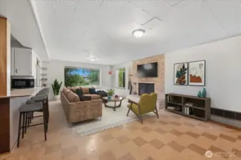 Virtually staged Rec Room with wood-burning fireplace.  Kitchenette on left with full size fridge, sink and cabinets.