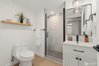 Updated 3/4 bath with new:vanity sink, Lit shower niche, floating shelf, floor to ceiling tile, penny tile, mirror, hardware and lighting sconce.