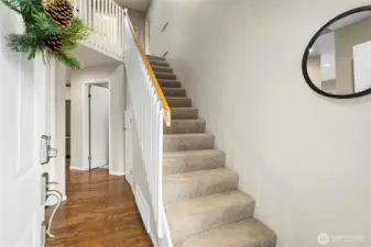 Entryway features warm hardwood flooring and a charming spindle rail design.