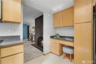 Transition area connecting the kitchen to a secondary living space featuring a brick fireplace and natural light.