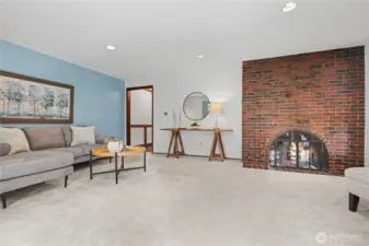 Secondary view of the main living area highlighting the brick fireplace, natural light, and spacious single-level layout.