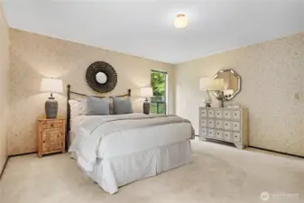 Spacious primary bedroom with large windows, soft natural light, and peaceful views of the surrounding greenery.