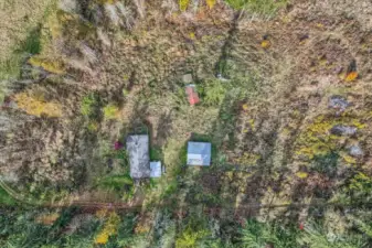 Overhead shot shows outbuildings- previous chicken coup.  4 stall horse barn. Roof is good condition.  Drive way near approximate property southern boundary line .