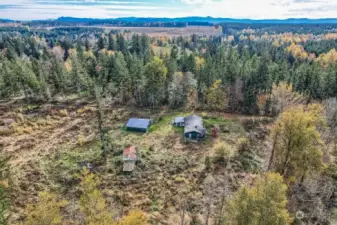 Looking from North to South.  A better veiw of the outbuilding, Barn and east entrance.  House is supported by septic system and is on this side of the property in both the front and back of the house according to the seller.  Buyer needs to verify all utilities and locations.