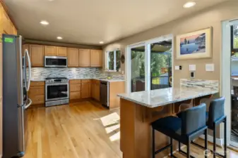 Kitchen w/eating island area, hardwood floors, quartz countertops, tile backsplash, another slider door leading out to the back deck, new paint and all new appliances!