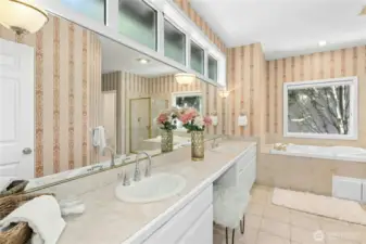Ample cupboard space and double sinks with natural light above make primary bath luxurious.