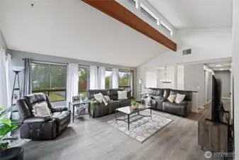 Step into a living space that instantly welcomes you with soaring vaulted ceilings and rich, exposed wood beams that add both architectural interest and warmth.
