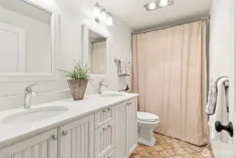 Main level full bathroom with double sinks granite countertops and a stylish vanity, tile flooring and tub/shower combination offering convenience and style for family and guests.