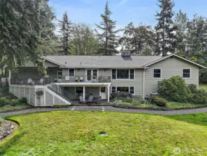 The back of the home showcases an expansive deck overlooking the beautifully landscaped, oversized lot, perfect for outdoor dining, entertaining, or simply taking in the peaceful surroundings. With multiple seating areas and a spacious yard, this property offers plenty of room to relax, play, and enjoy the best of indoor-outdoor living.