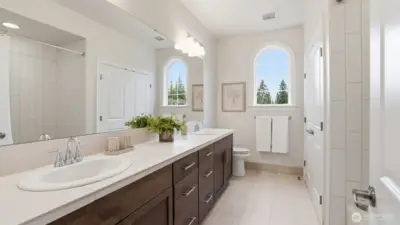 Expansive hall bath servicing 2 bedrooms with dual vanities, tile surround tub/shower, large linen closet and tile floors.