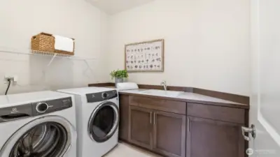 Convenient upper level laundry room with utility sink and an abundance of work space