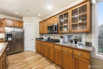 Elegant wood cabinetry compliments the hardwood flooring. Peekaboo window looking out to the community park while you cook at the gas stove. Display cabinetry pair at end of top cabinets perfect for showing of your china set.