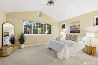 Large primary suite with vaulted ceiling and ceiling fan. Abundant natural light from huge window and additional smaller windows.