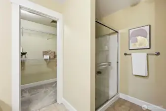 Walk-in shower with glass sliding doors to right of the walk-in closet entrance.